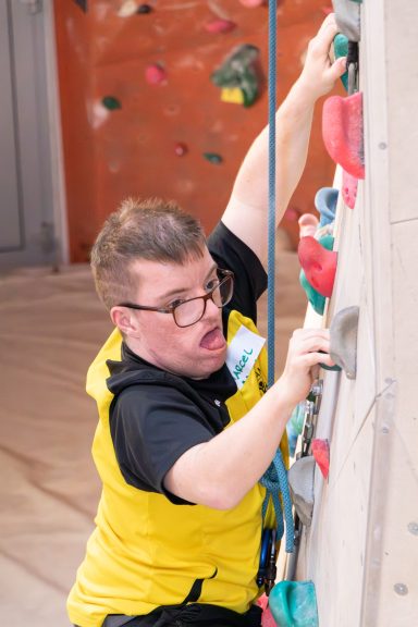 Person klettert an einer Boulderwand in einem Sportzentrum.