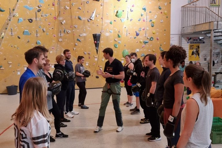 Gruppenschulung in einer Kletterhalle mit Teilnehmern und einem Trainer.