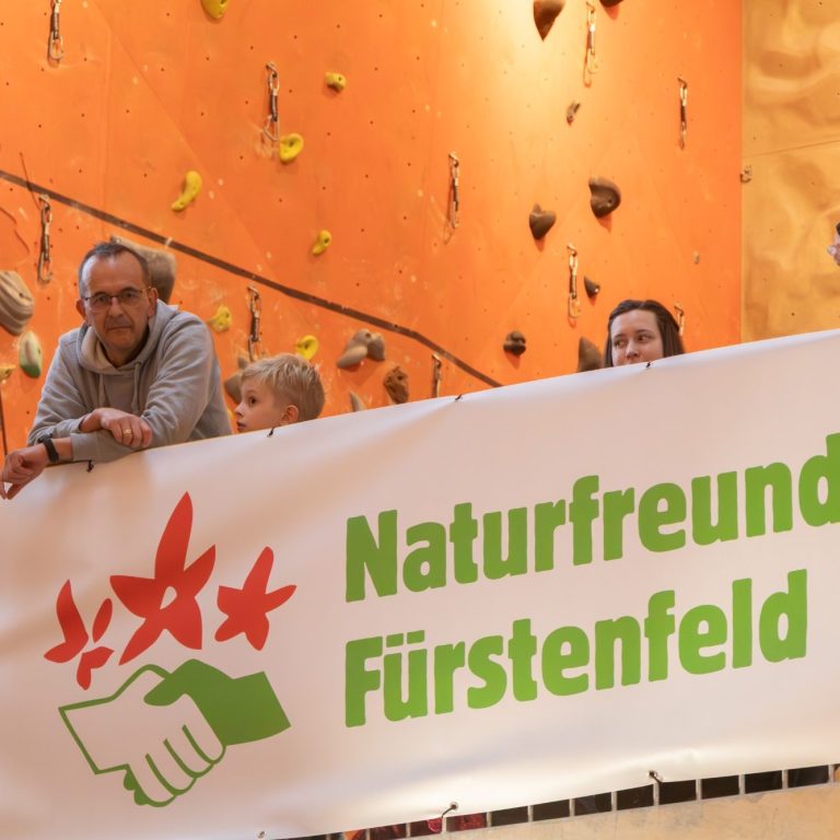Banner mit der Aufschrift „Naturfreunde Fürstenfeld“ und Zuschauer darüber.